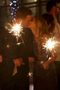 two people kissing while holding sparklers in their hands