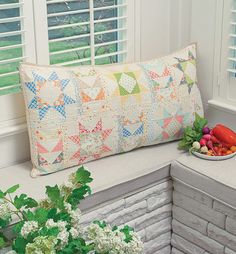 a pillow sitting on top of a brick wall next to a plate of fruit and vegetables