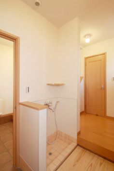 an empty bathroom with wooden floors and tile flooring, including a shower head in the corner