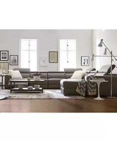 a living room filled with lots of furniture next to a large white wall and windows