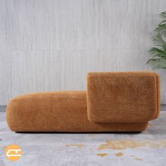 an orange couch sitting on top of a carpeted floor next to a potted plant