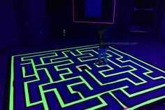 a person standing in front of a maze on the floor with neon green and blue lights