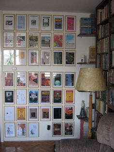 a living room filled with lots of books on the wall next to a chair and lamp