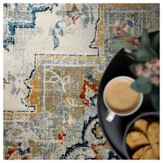 a plate with some cookies and a cup of coffee on it next to a rug