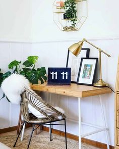 a wooden desk topped with a lamp next to a chair and potted green plant