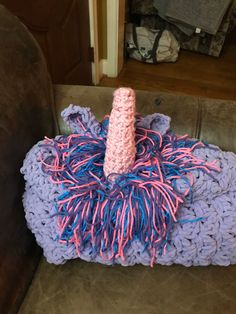 a crocheted pillow with a pink and blue unicorn horn sitting on top of it