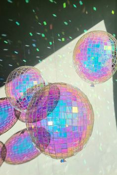 several disco balls hanging from strings with confetti in the background