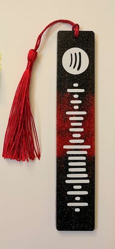 a bookmark with a red tassel on top of it next to a flower