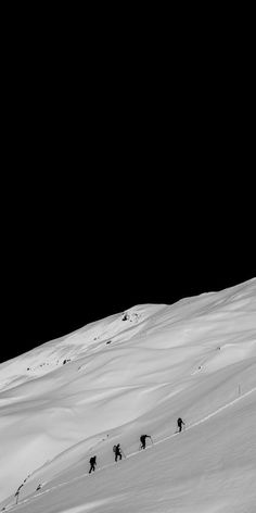 three skiers are skiing down a snowy hill at night time with the moon in the background