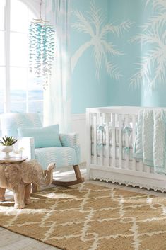 a baby's room decorated in blue and white with palm trees on the wall