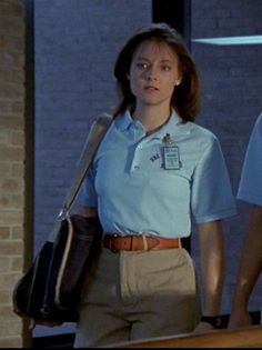 two women in uniforms are walking down the street, one is carrying a bag and the other has a purse on her shoulder