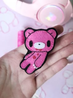 a hand holding a pink teddy bear patch