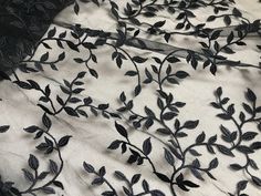 black leaves and vines on white fabric with sheer netting over the top, closeup