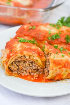 a white plate topped with lasagna covered in sauce