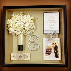 a wedding gift with flowers and pictures in a shadow box on the wall next to it