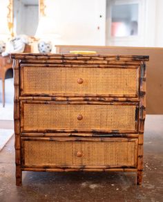 an old bamboo dresser with two drawers on it's sides, in front of a mirror