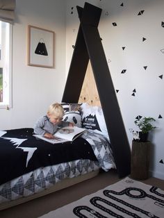 a young boy laying in bed reading a book