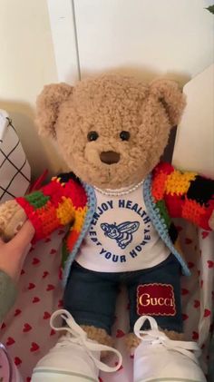 a teddy bear sitting in a child's crocheted chair with shoes on