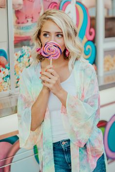 a woman holding a lollipop in front of a carousel