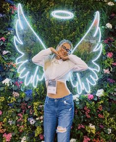 a woman standing in front of a flower wall with an angel on it's back