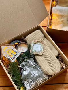 an open box filled with items on top of a wooden floor next to a candle