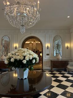 a large vase with white flowers on top of a black and white checkered floor