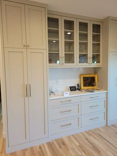 an empty kitchen with white cabinets and wood flooring, in the middle of a room