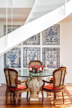 a dining room table with chairs under a stair case and pictures on the wall behind it