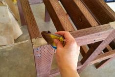 a person is holding a piece of wood in their hand while they are working on some furniture