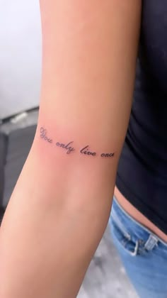 a woman with a tattoo on her arm that says, we only live once