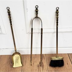 three brooms are lined up next to each other on the floor in front of a door