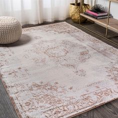 a beige rug with an ornate design on the floor in front of a white curtain