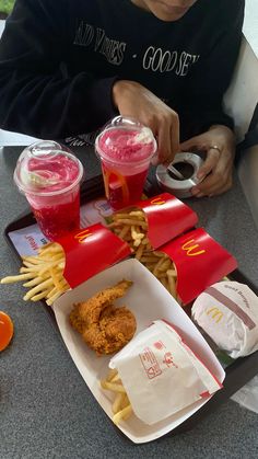 a person sitting at a table with some food and drinks in front of them,