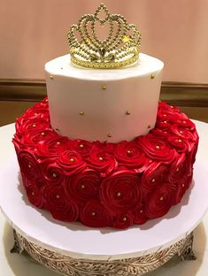 two tiered cake decorated with red roses and a gold crown