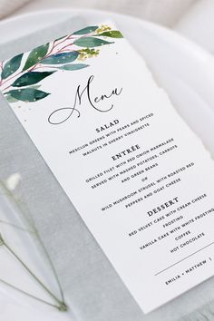 a white plate topped with a menu card on top of a silver and white table cloth