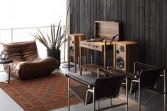 a living room filled with furniture next to a wall mounted speaker and plant in the corner