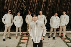 a group of young men standing next to each other in front of bamboo trees and grass