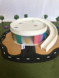 a model of a round building with colorful doors on the side and trees in the background