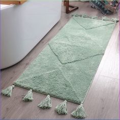 a green rug with tassels on the floor in a living room or bathroom