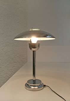 a table lamp sitting on top of a white counter next to a light switch and plugged in