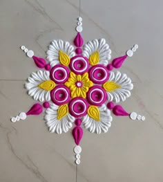 an intricate design on the floor with white and yellow accents, including pink flowers in center