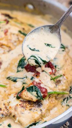 a ladle scooping some food out of a pot filled with cheese and spinach