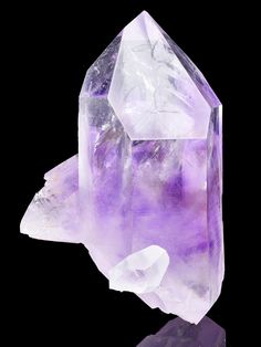 an ametholite crystal with purple hues and white crystals on a black background