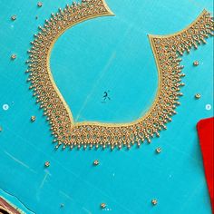 a blue table topped with lots of gold beads and a piece of red scissors next to it