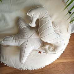 a large white pillow sitting on top of a wooden floor next to a potted plant