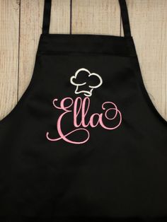 an apron with the word ella on it and a chef's hat in pink