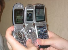 a person holding three cell phones in their hands