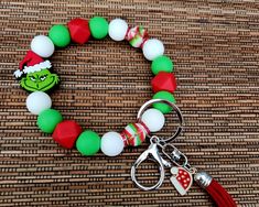 a green and red bracelet with a white bead on it, featuring the grinch head