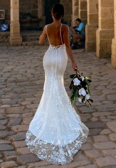 a woman in a wedding dress walking down the street with her back to the camera