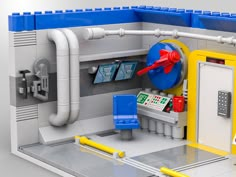 a lego model of a control room with pipes and valves on the wall, next to a phone